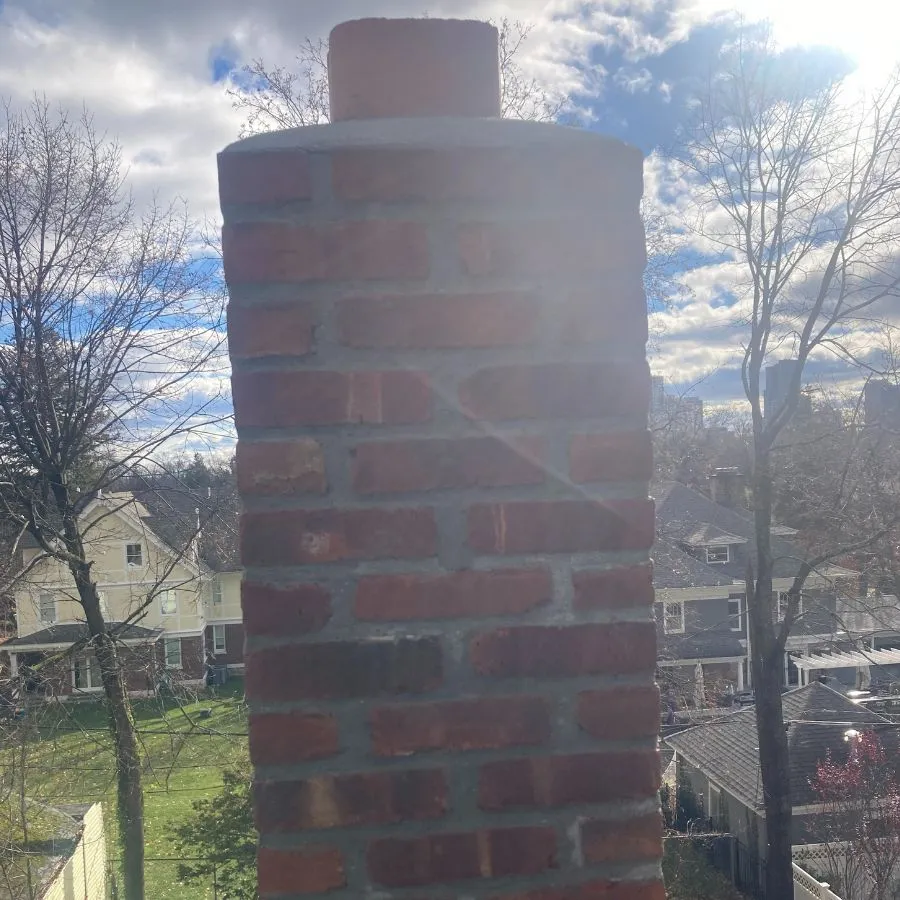 Brick chimney top with mortar joints under sunny sky