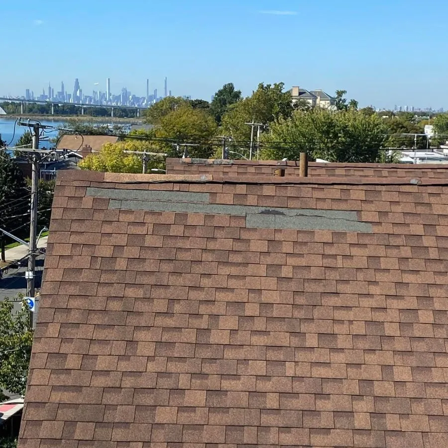 Missing asphalt shingles on pitched roof with skyline view