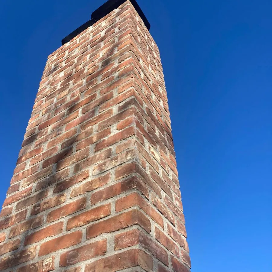 Upward view of clean brick chimney under clear blue sky